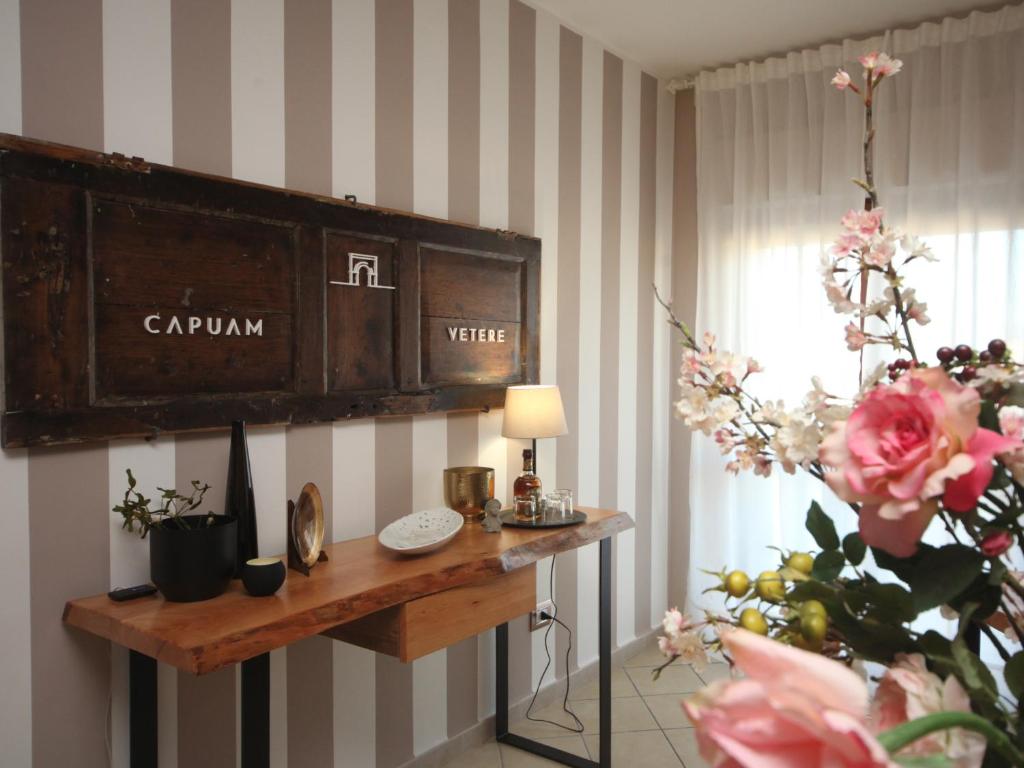 una stanza con tavolo con orologio e fiori di B&B Capuam Vetere Accommodation a Santa Maria Capua Vetere