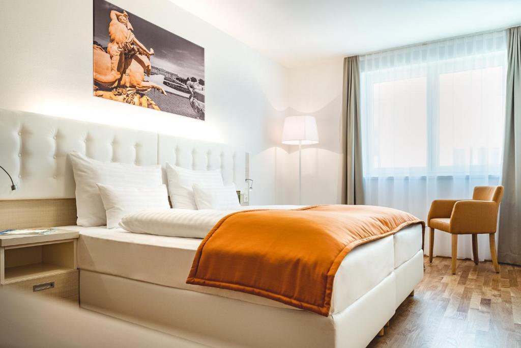 a white bedroom with a large bed with an orange blanket at Oliver Apartments | contactless check-in in Vienna