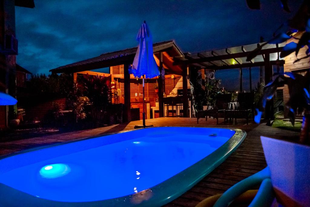 a blue swimming pool in a backyard at night at Villa Rosa e Mar - Praia do Rosa in Imbituba