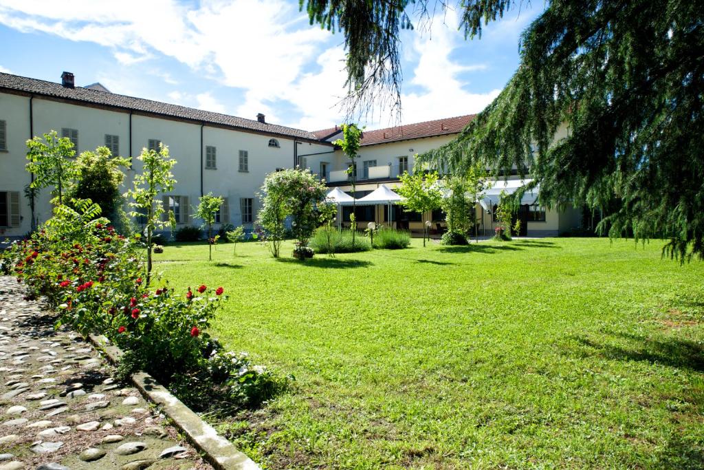 un bâtiment avec une cour fleurie devant elle dans l'établissement Il Convento, à Trino