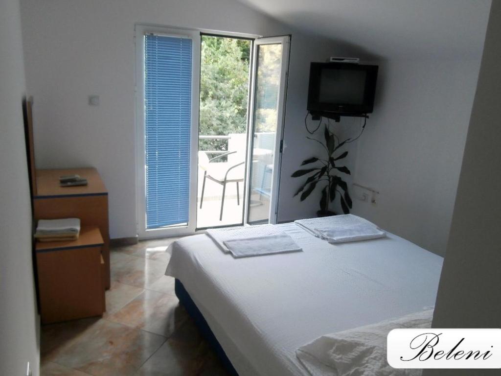 1 dormitorio con 1 cama y balcón con TV en Apartments Beleni, en Herceg-Novi