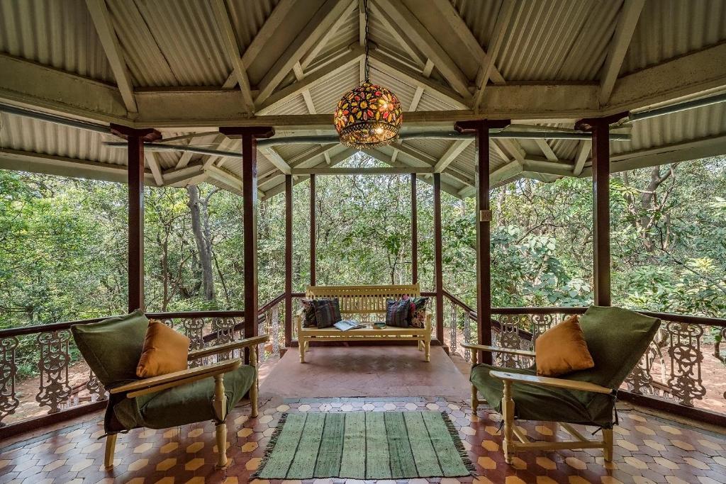 eine abgeschirmte Veranda mit Stühlen und einem Kronleuchter in der Unterkunft SaffronStays Parsi Manor - 4-BR heritage villa near Charlotte Lake serving authentic Parsi meals in Matheran