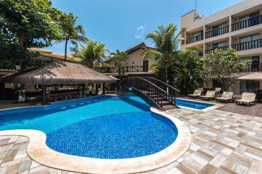 a swimming pool in front of a building at Pousada Recanto do Lobo in Porto De Galinhas