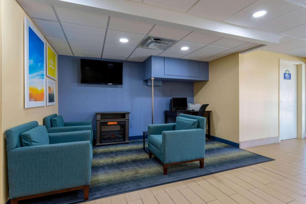 una sala de espera con sillas azules y TV en Days Inn by Wyndham Augusta, en Augusta