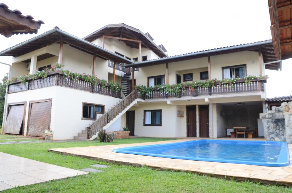 a villa with a swimming pool in front of a house at Pousada Adler in Treze Tílias