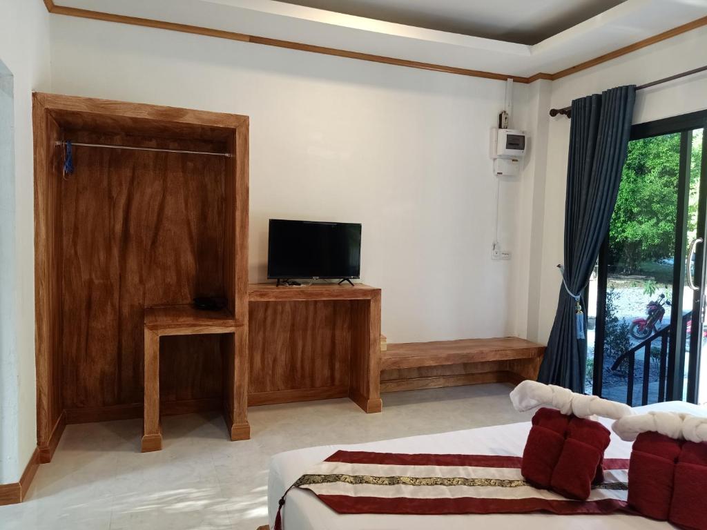 a bedroom with a bed and a tv and a window at Lanta Buddy Resort in Ko Lanta