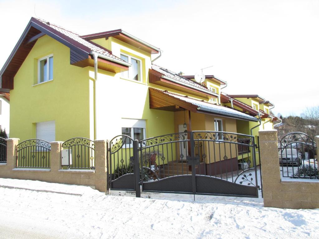 una casa amarilla con una puerta en la nieve en Apartmany Jaruska en Nová Lesná