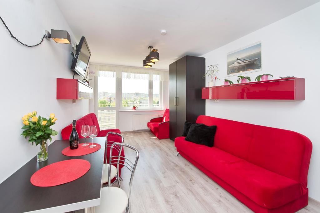 Apartament Słoneczne Południe في غدانسك: غرفة معيشة مع أريكة حمراء وطاولة