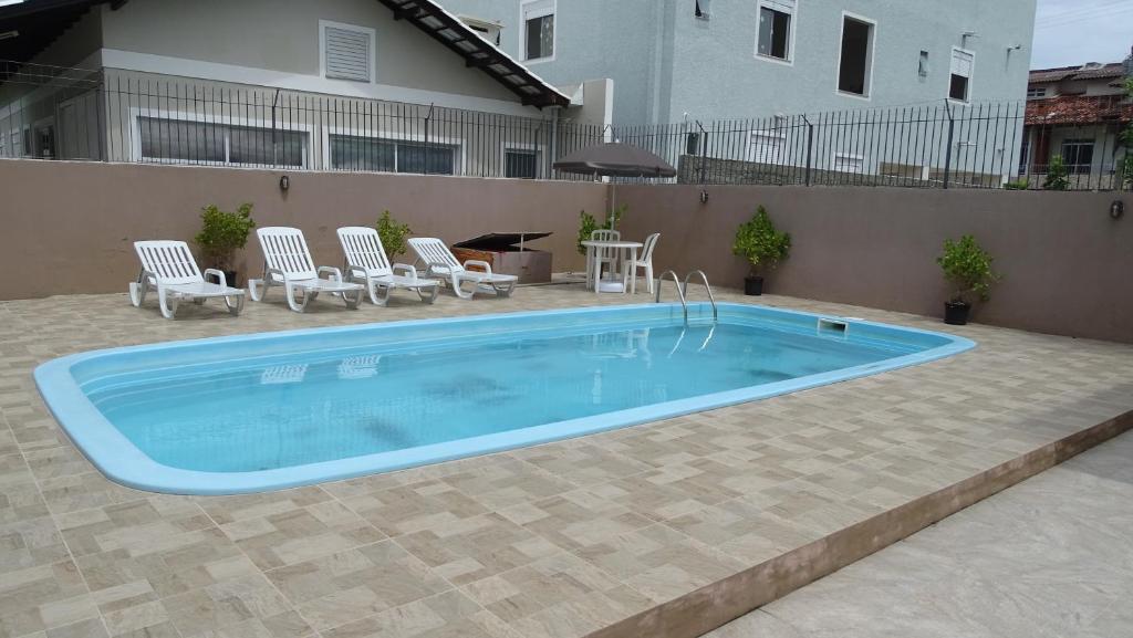 una gran piscina con sillas y una casa en Condominio Horizontal União, en Florianópolis