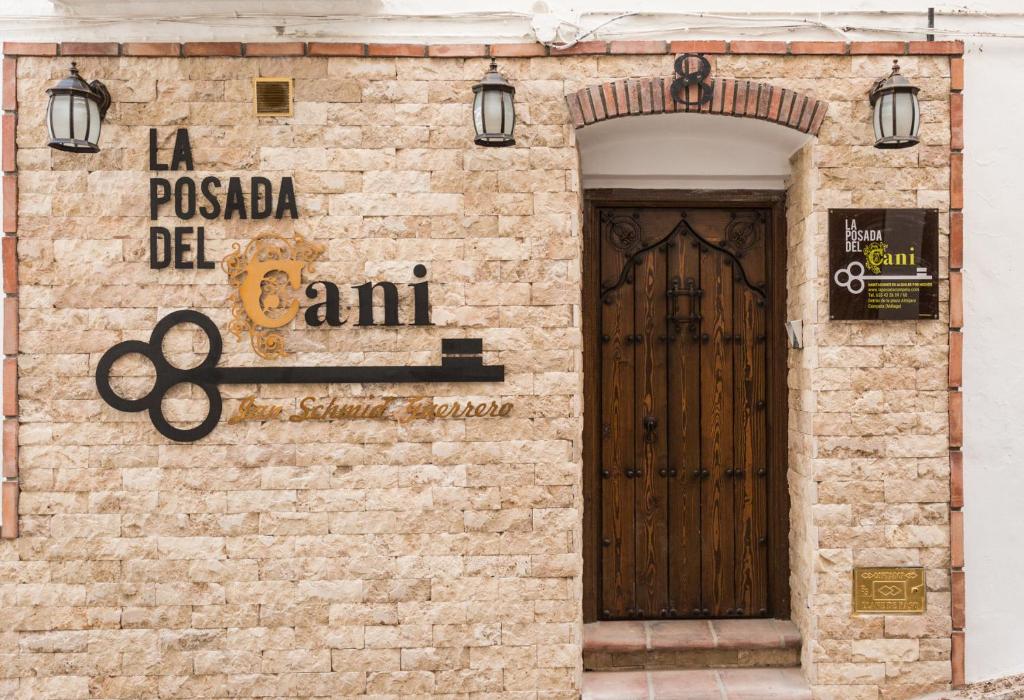 um edifício de tijolos com uma porta e um cartaz em La posada del Cani em Cómpeta