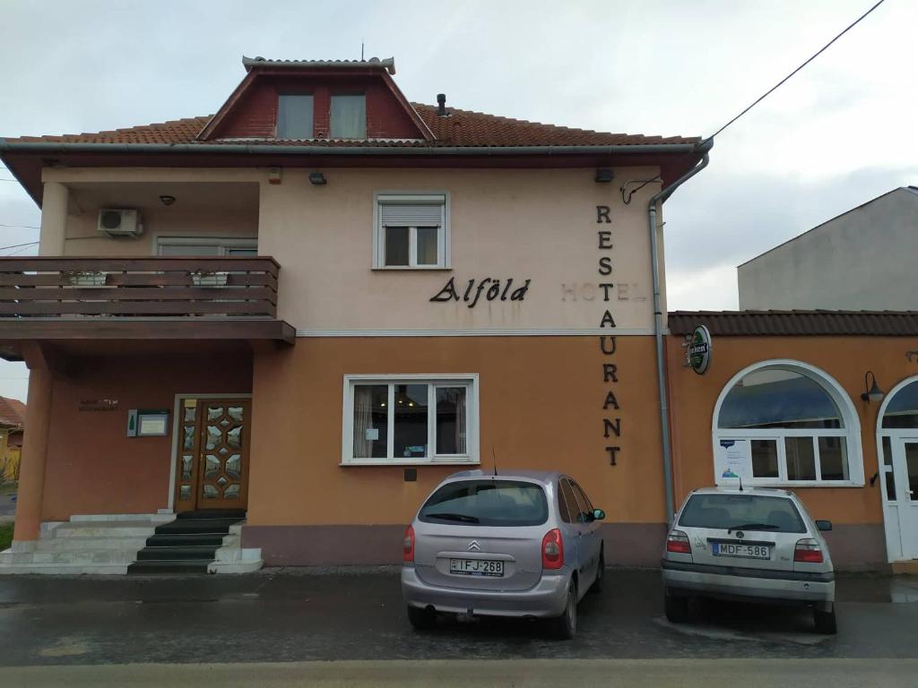 two cars parked in front of a building at Alföld Panzio & Étterem in Cegléd