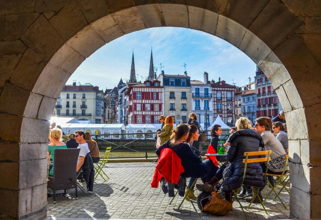 un groupe de personnes assises à des tables sous une arche dans l'établissement bayonne centre, à Bayonne