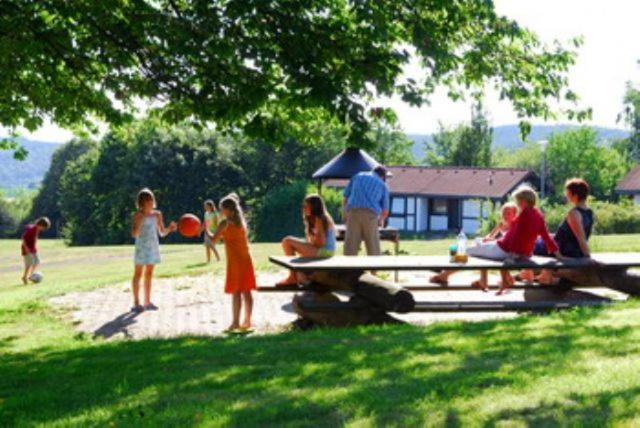 a group of people sitting around a picnic table in a field at Type Winnetou in Ronshausen