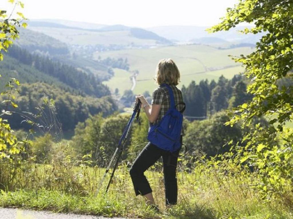 a woman with a backpack standing on the side of a road at Typ Murmeltier in Schmallenberg