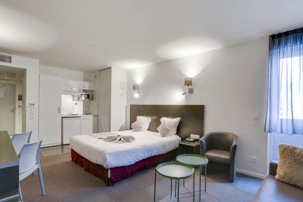 ランジスにあるAll Suites Appart Hôtel Aéroport Paris Orly – Rungisのベッド、テーブル、椅子が備わるホテルルームです。
