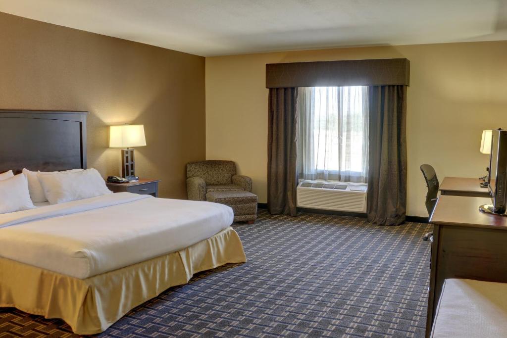 a hotel room with a bed and a chair at Holiday Inn Express Hotel & Suites Texarkana East by IHG in Texarkana