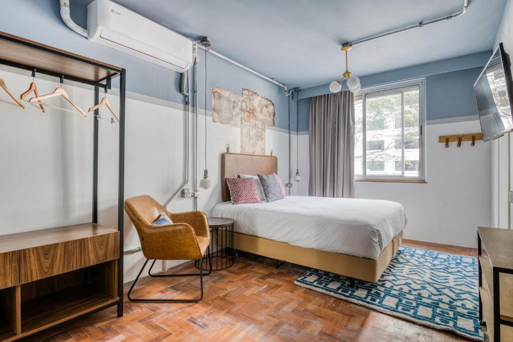 een slaapkamer met een bed en een stoel erin bij Selina Aurora Sao Paulo in Sao Paulo