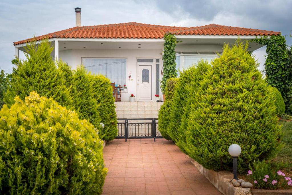 a house with green bushes in front of it at Vineyard Country House with Panoramic Seaview in Alexandroupoli