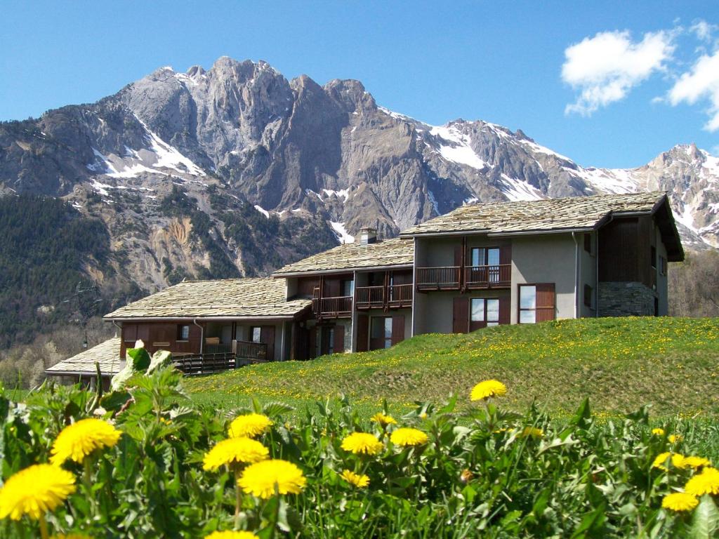 una casa in cima a una collina con fiori gialli di Gîte Le Shantoné a Saint-Michel-de-Maurienne