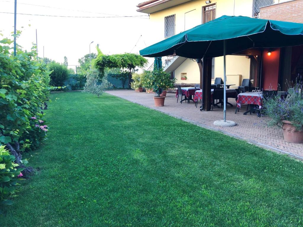 eine Terrasse mit einem Tisch und einem Sonnenschirm im Hof in der Unterkunft Da Nando Antica Osteria Hotel in Godi