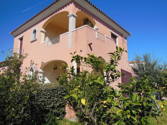 un grand bâtiment rose avec un balcon. dans l'établissement Gramsci 3, à San Teodoro