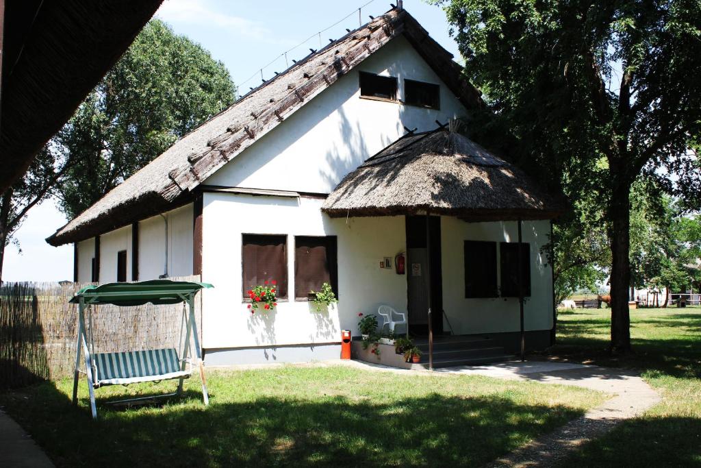 una pequeña casa blanca con techo de paja en Patkós Motel, en Tiszafüred