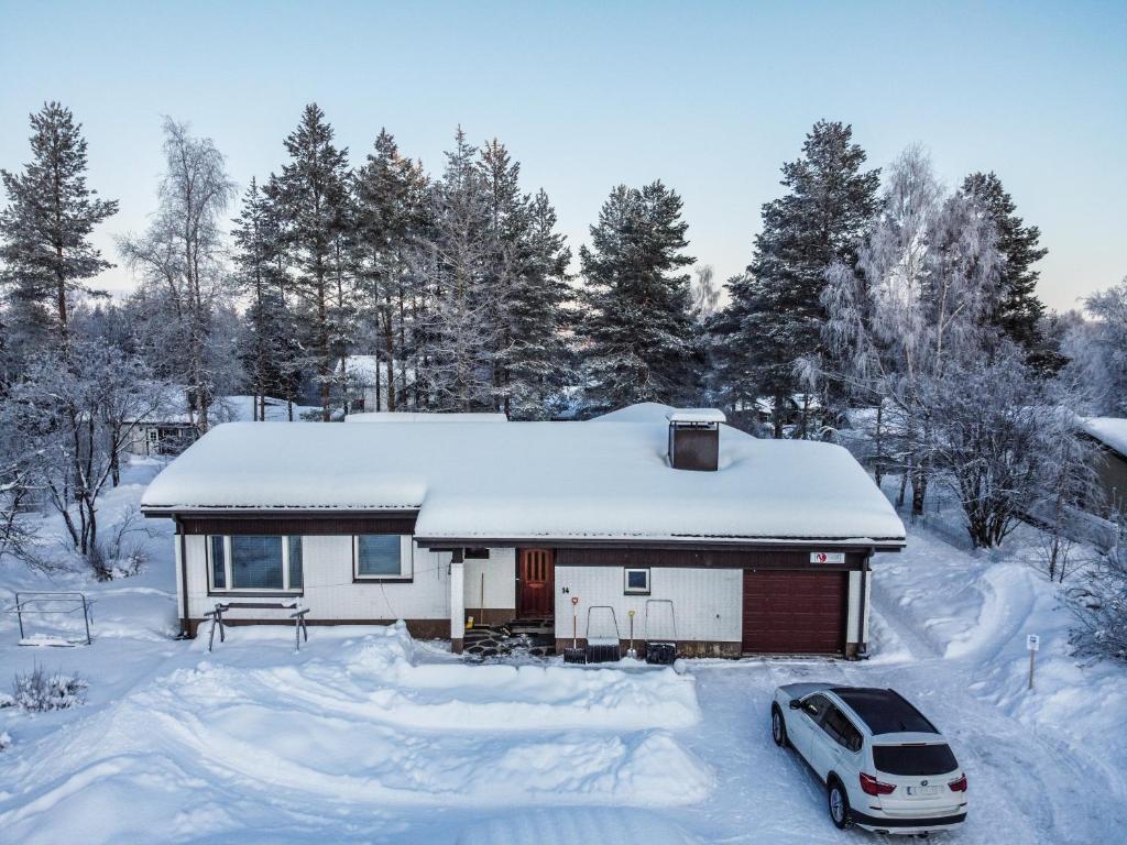 a house with a car parked in the snow at Foxtail Apartment in Rovaniemi