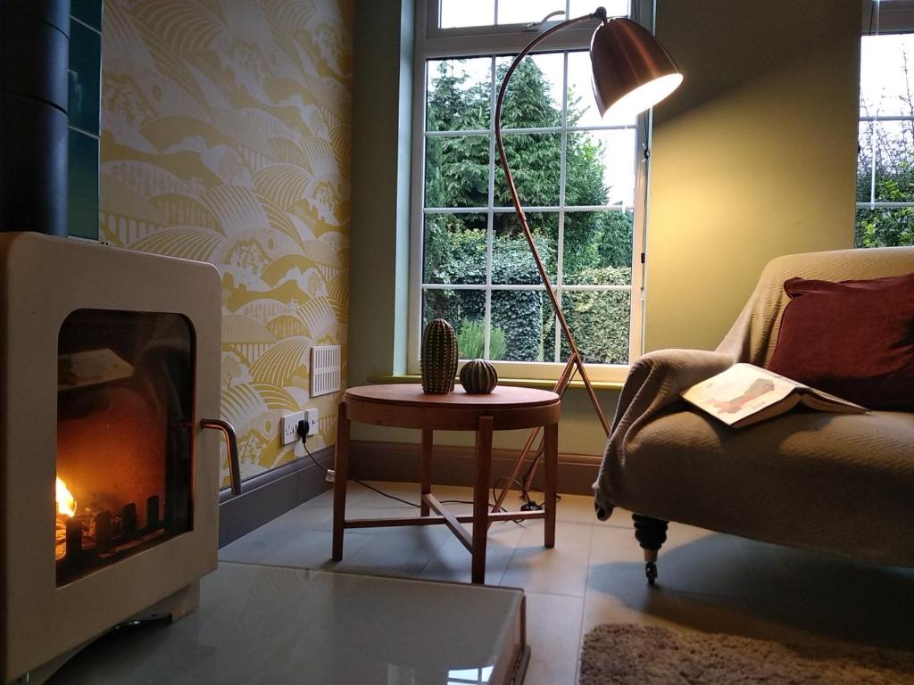 een woonkamer met een open haard en een stoel bij The Whimsy 2 bedroom cottage in National Forest, private parking & garden in Blackfordby