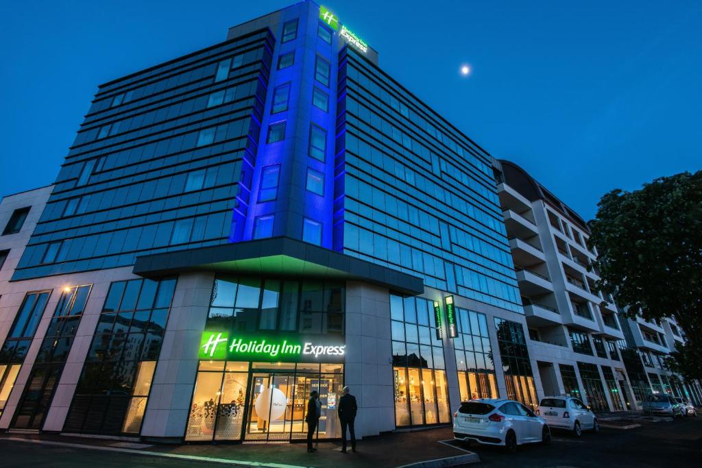 un grand bâtiment avec un panneau bleu éclairé dans l'établissement Holiday Inn Express - Rouen Centre - Rive Gauche, an IHG Hotel, à Rouen