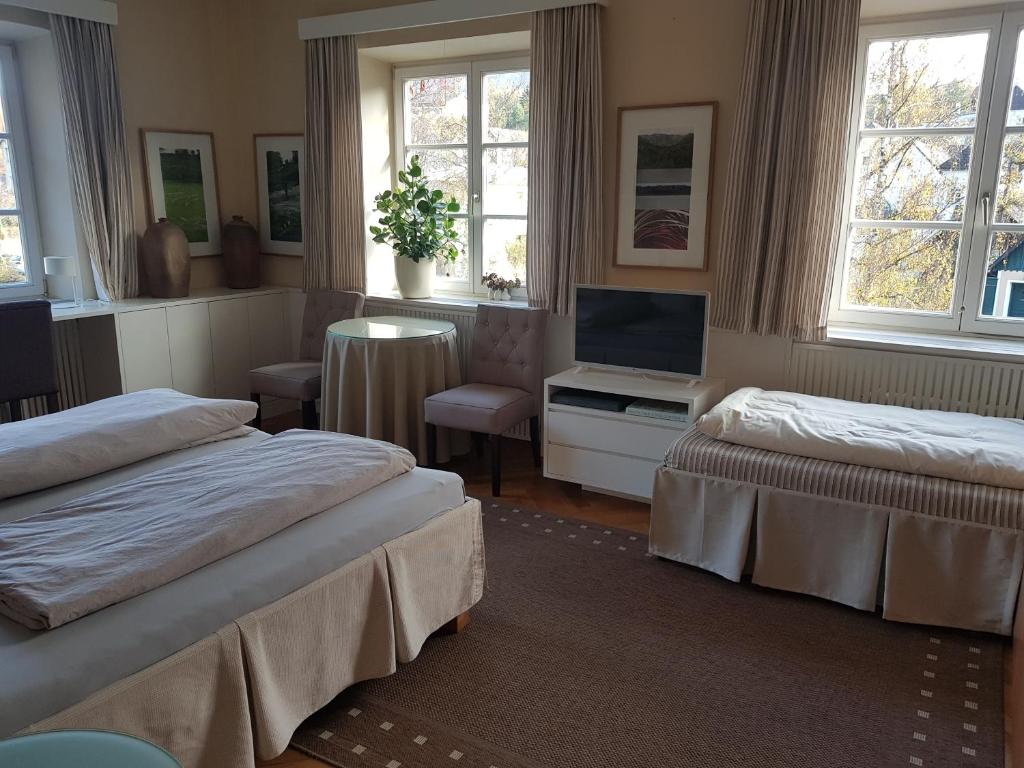 a bedroom with two beds and a tv and windows at Gästehaus Grogger in Weyer Markt
