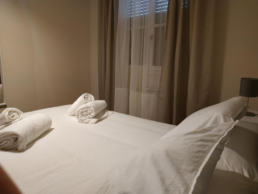 białe łóżko z ręcznikami i oknem w obiekcie Pilatos w mieście Zamora