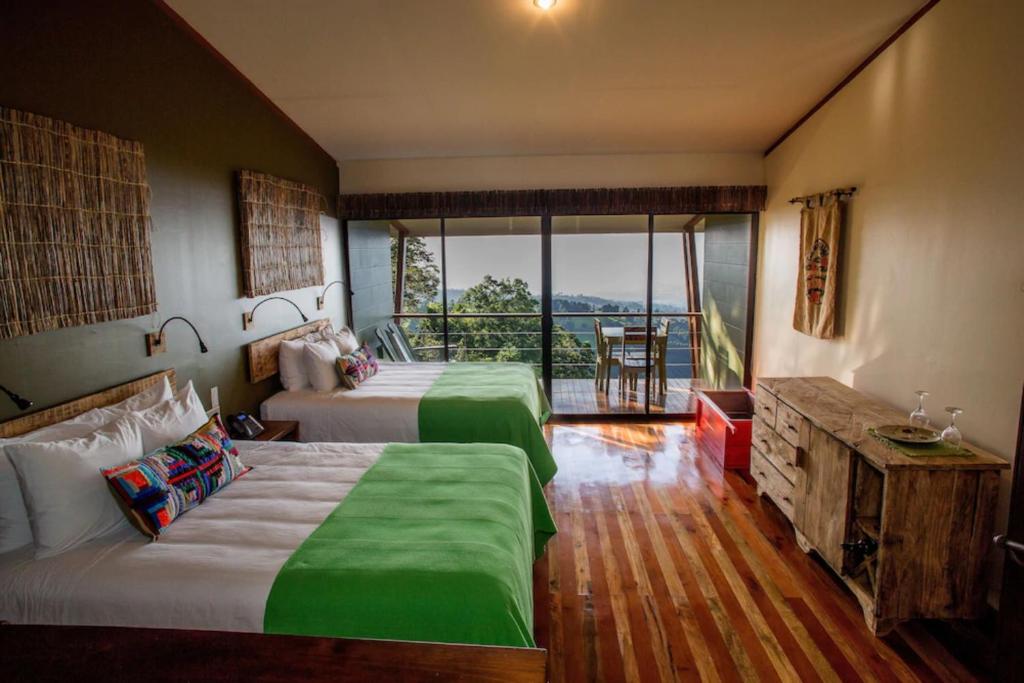 a hotel room with two beds and a balcony at Chayote Lodge in Zarcero