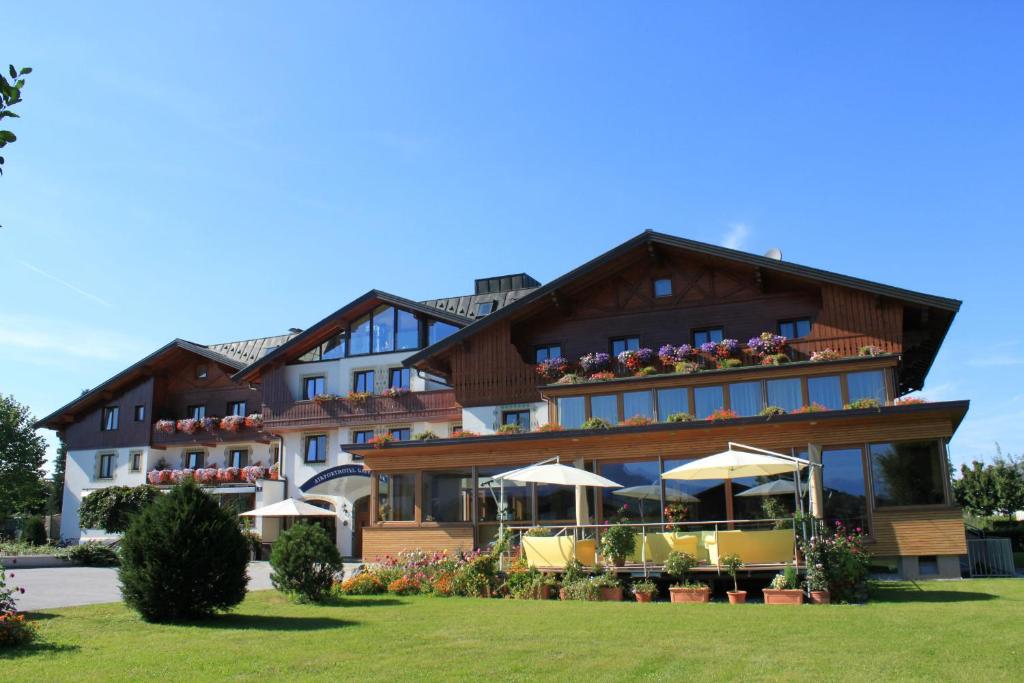 ein Hotel mit Tischen und Sonnenschirmen davor in der Unterkunft Airporthotel Salzburg - Hotel am Salzburg Airport in Salzburg