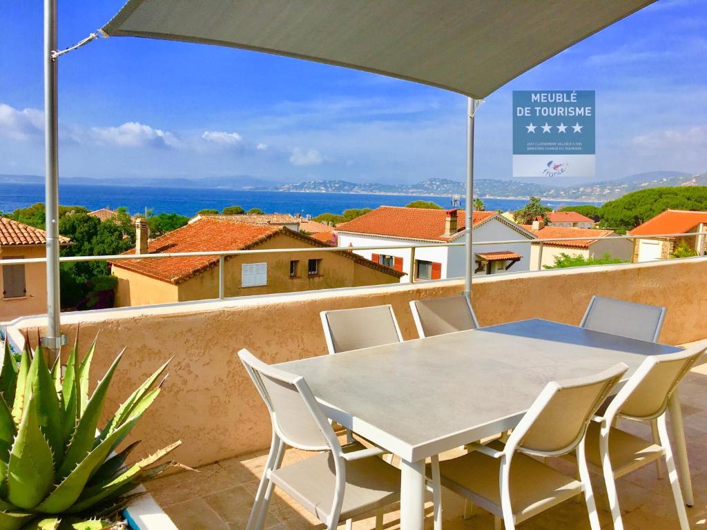 einen Tisch und Stühle auf einem Balkon mit Sonnenschirm in der Unterkunft Appartement avec splendide vue mer, à 200 m de la plage, Golfe de Saint-Tropez in Les Issambres