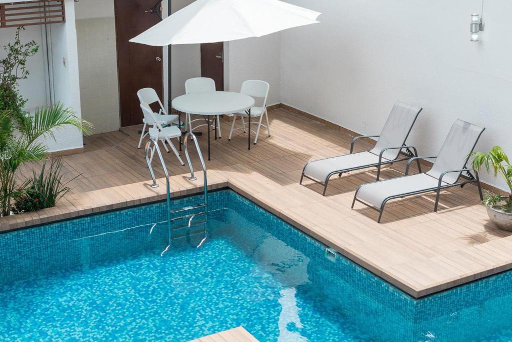une terrasse avec une table, des chaises et une piscine dans l'établissement Fiori Apartments, à Santa Cruz de la Sierra
