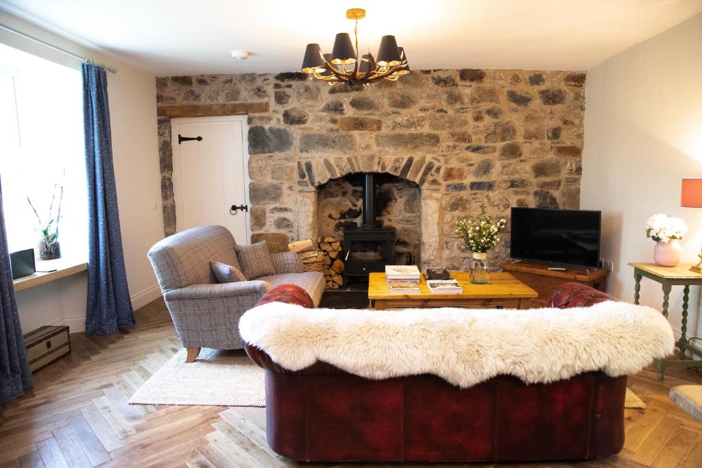 a living room with a stone fireplace and a couch at Dandaleith Cottage No.1 in Craigellachie