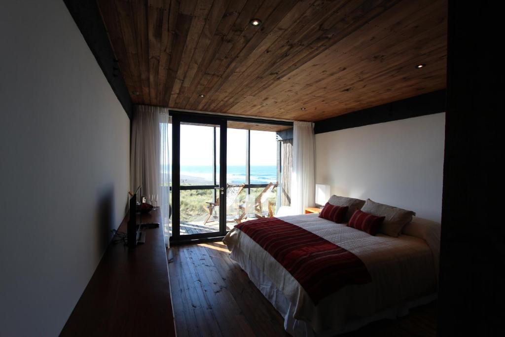 a bedroom with a bed and a large window at Hotel Punta Sirena in Curanipe