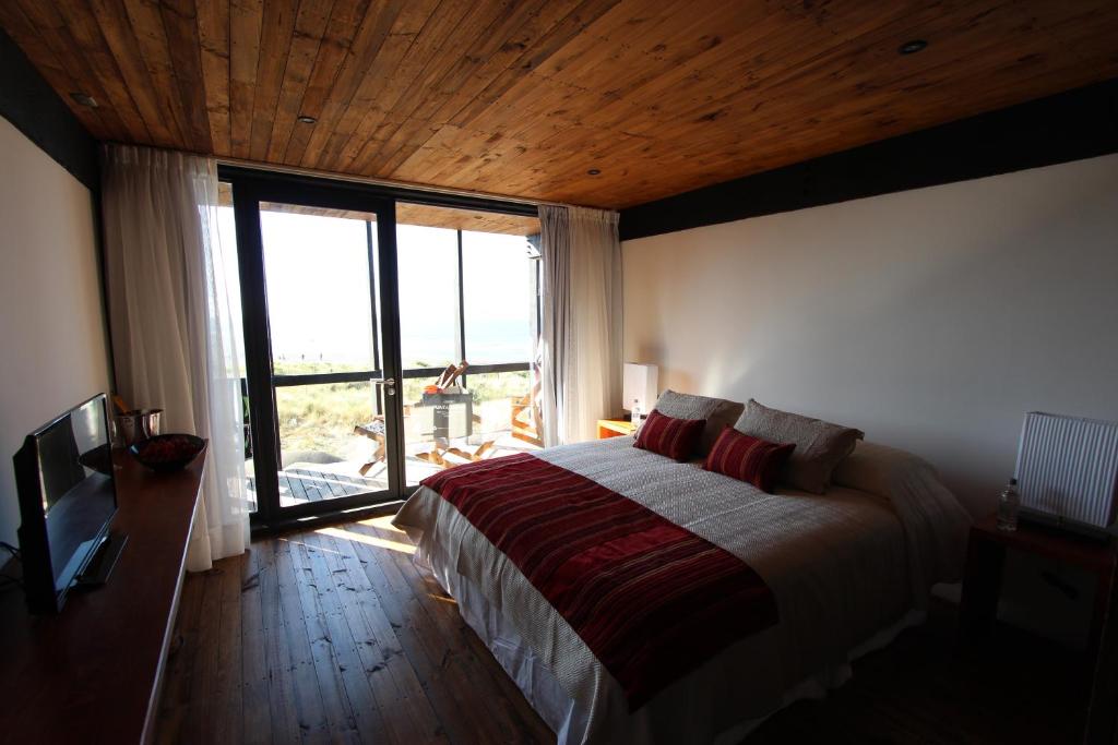 a bedroom with a bed and a large window at Hotel Punta Sirena in Curanipe