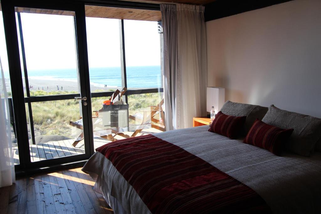 a bedroom with a bed and a view of the ocean at Hotel Punta Sirena in Curanipe