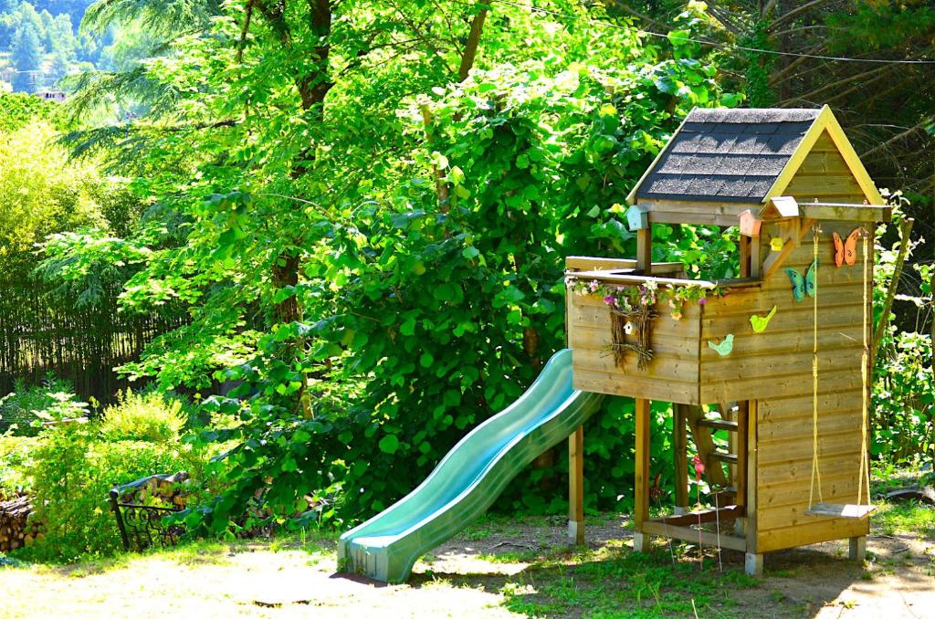 a wooden playground with a slide and a house at Mas Mialou in Saint-Jean-du-Gard