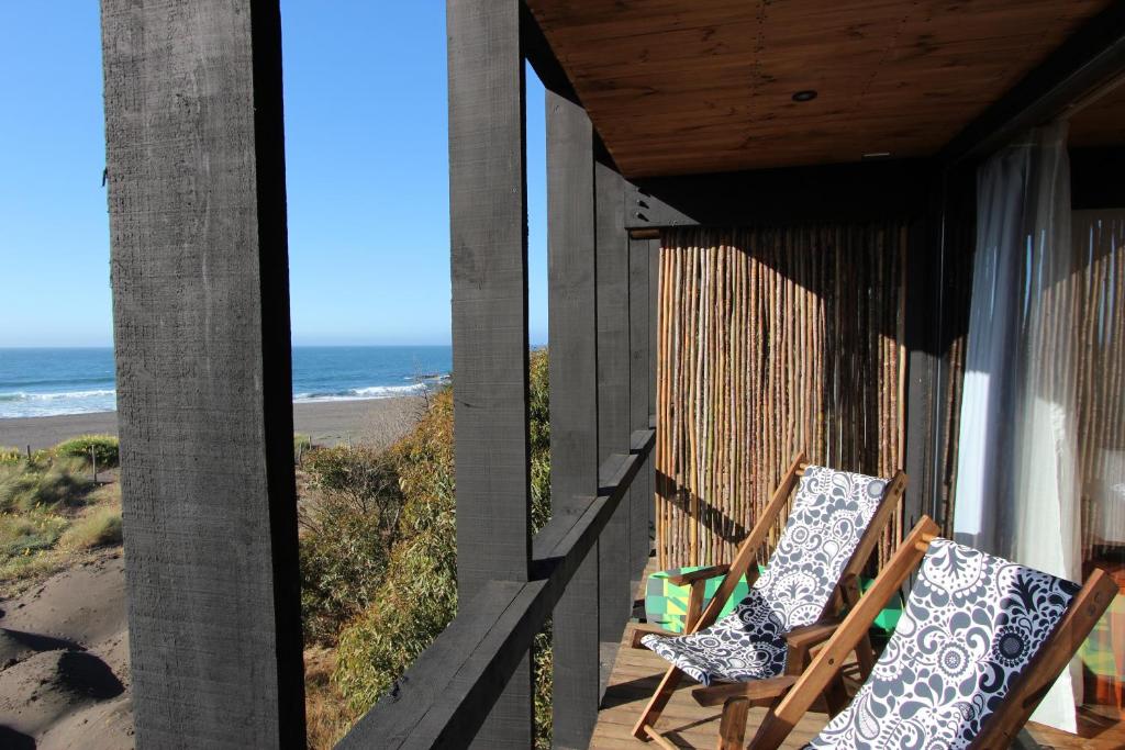 two chairs sitting on a porch looking out at the beach at Hotel Punta Sirena in Curanipe