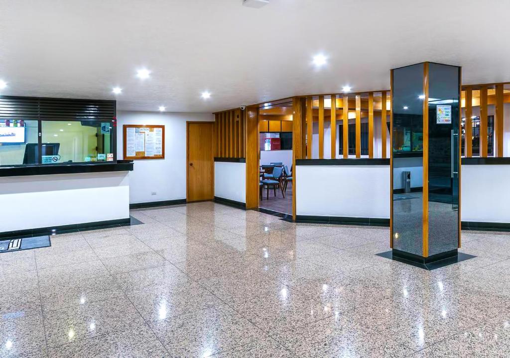 A bright reception lobby with a long desk, wood partitions, and polished stone flooring.