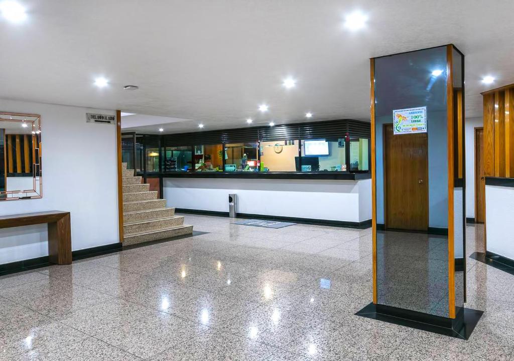 A reception lobby with stairs, a front desk, a bench, and a large mirrored column.