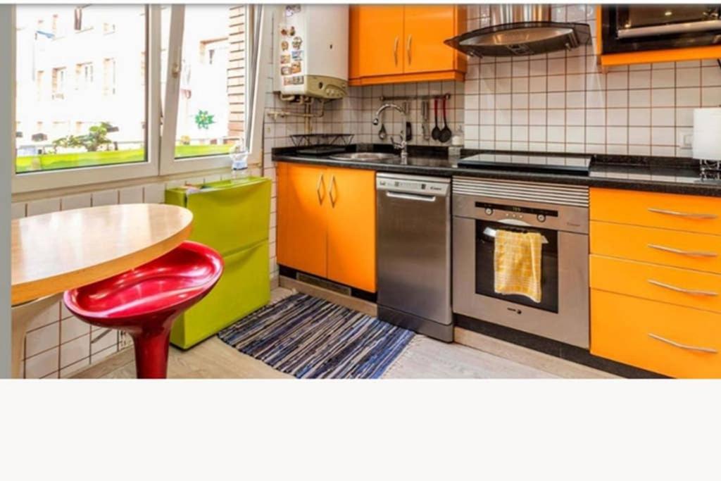 une cuisine avec des armoires orange et une table avec un tabouret rouge dans l'établissement ComfortStyle, à Oviedo