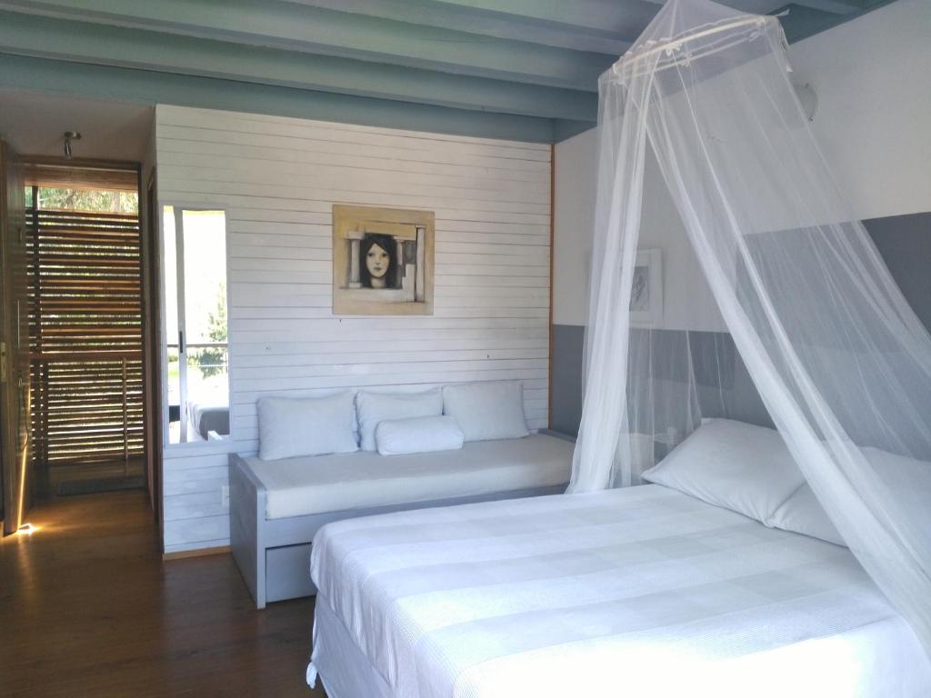 1 dormitorio con 1 cama blanca con dosel en La Pedrasanta, en La Pedrera