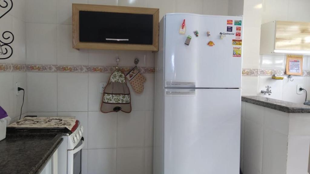 a kitchen with a refrigerator and a tv on the wall at Cobertura Aconchegante Itaúna in Saquarema