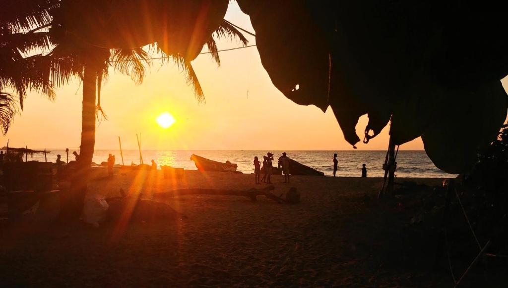 um grupo de pessoas em uma praia ao pôr do sol em Grace Homestay em Negombo