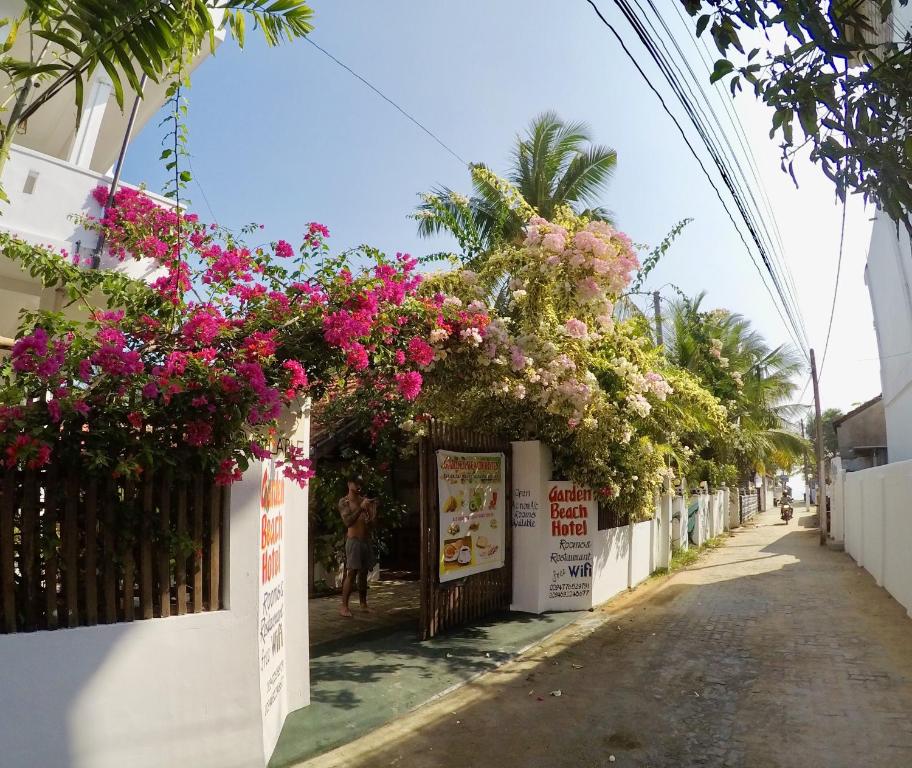 ulica z kwiatami wiszącymi z budynku w obiekcie Garden Beach Hotel w mieście Arugam Bay