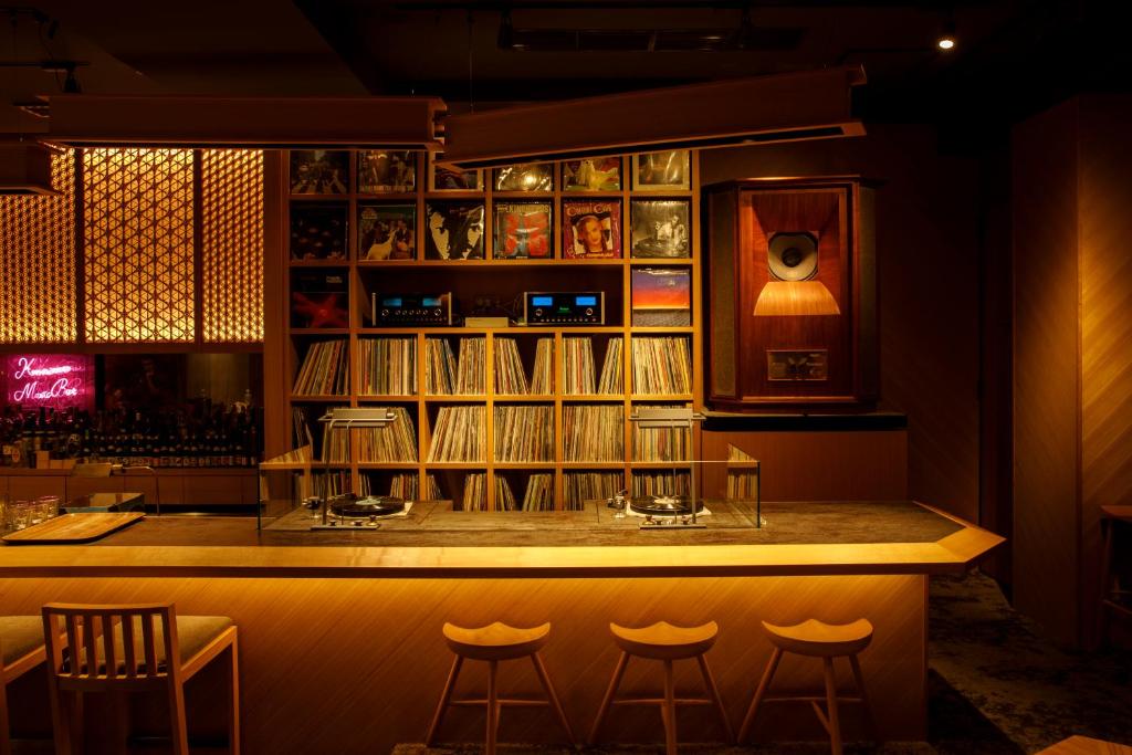 um bar com algumas cadeiras e uma prateleira com livros em Kaname Inn Tatemachi em Kanazawa