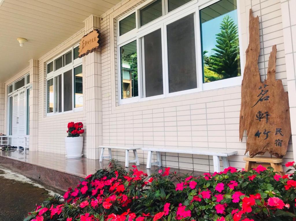 ein Haus mit roten Blumen auf der Veranda in der Unterkunft Riley Ming Xuan B&B in Meishan